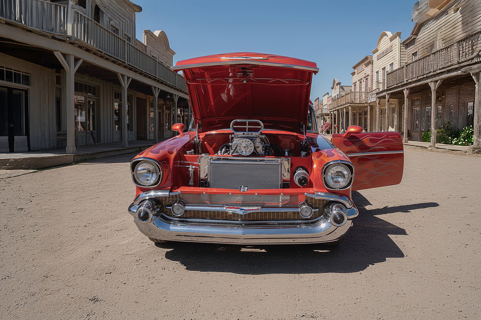 A vintage red car with flames painted on its sides, parked on a dirt street with its hood open revealing a supercharged engine. The scene is set in a Western-style town with wooden buildings on either side.