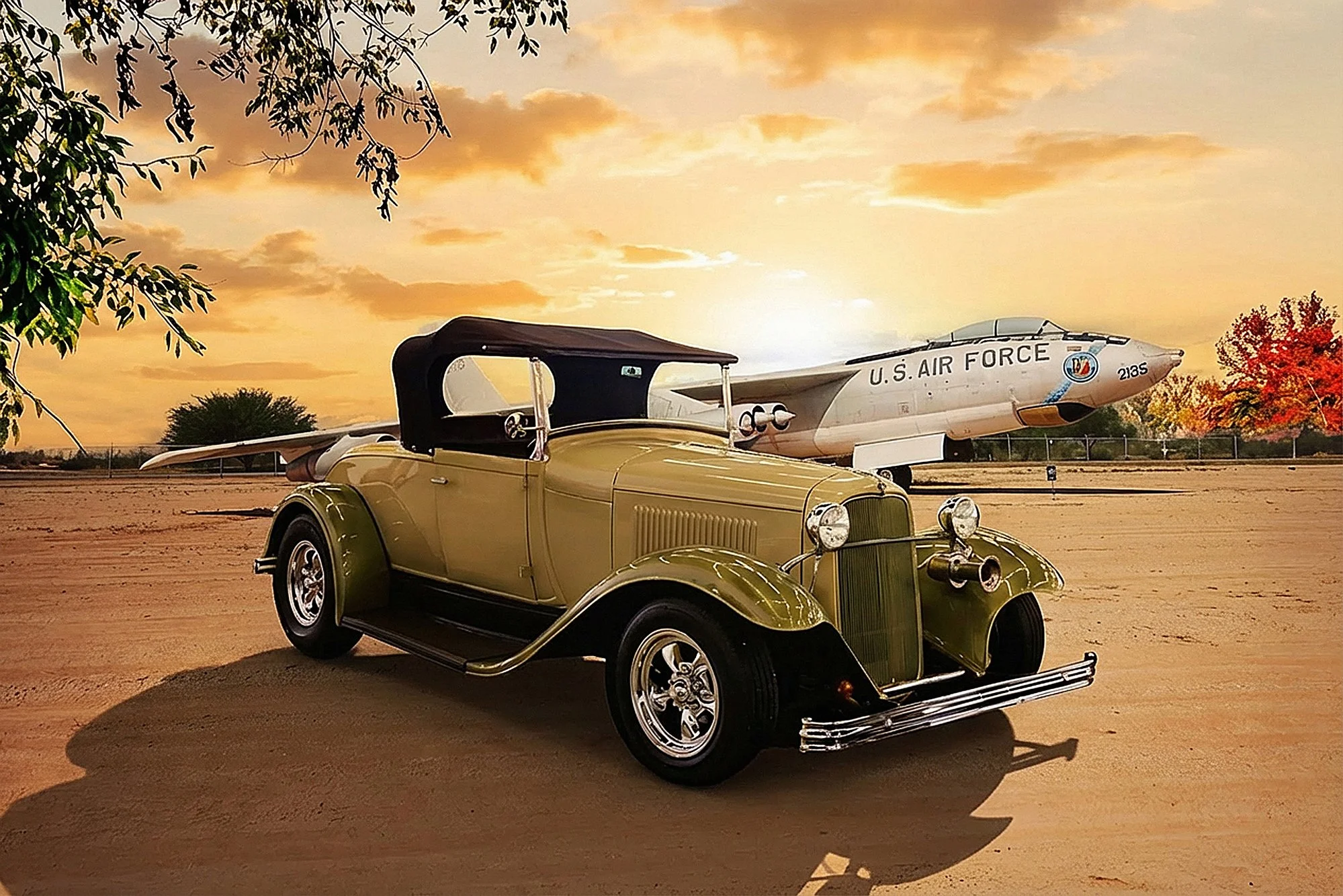 A vintage green car parked on a dirt path with a stormy sunset sky and a U.S. Air Force aircraft in the background. There are trees with fall foliage nearby.