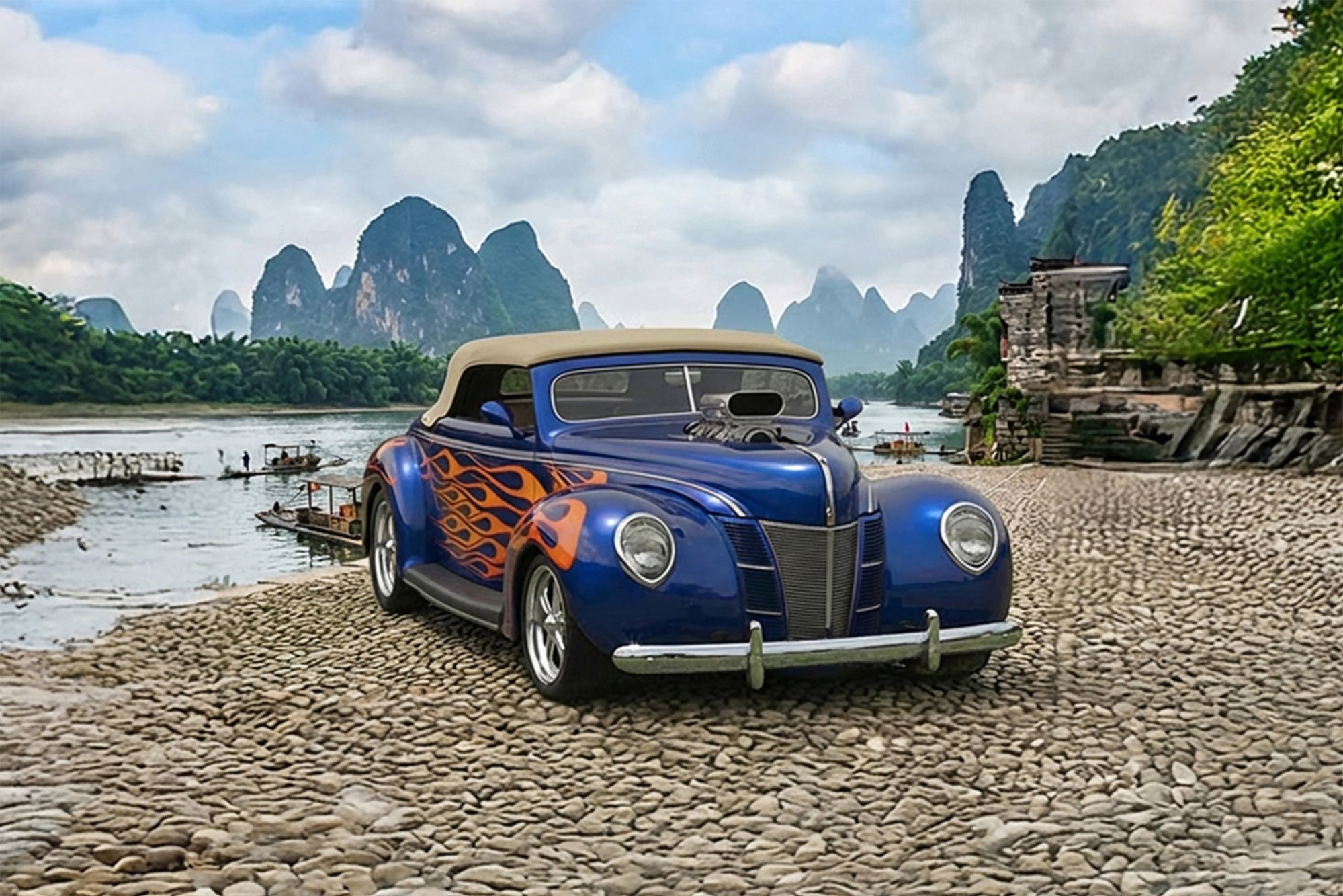 A vintage blue car with flame decals parked on a rocky riverbank with river boats and limestone karst mountains in the background.
