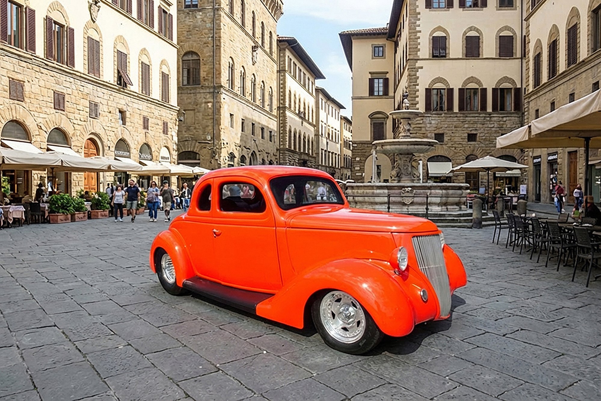 A bright red vintage car parked in a European city square with historic stone buildings, outdoor cafes, and a water fountain.