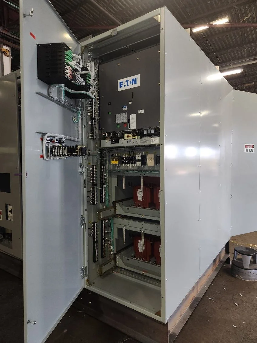 An industrial electrical control panel with open door, showing circuit breakers, wiring, and components inside, branded with Eaton logo.