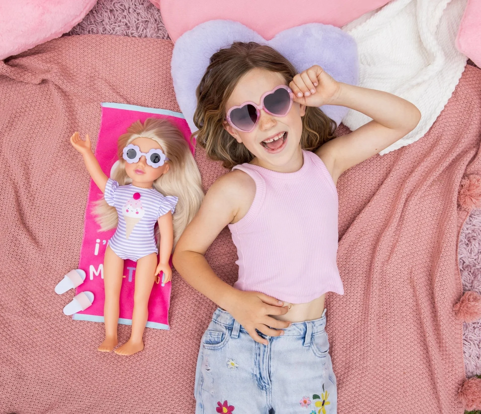 Young girl lying on the floor with her DesignAfriend doll, smiling up at the camera.
