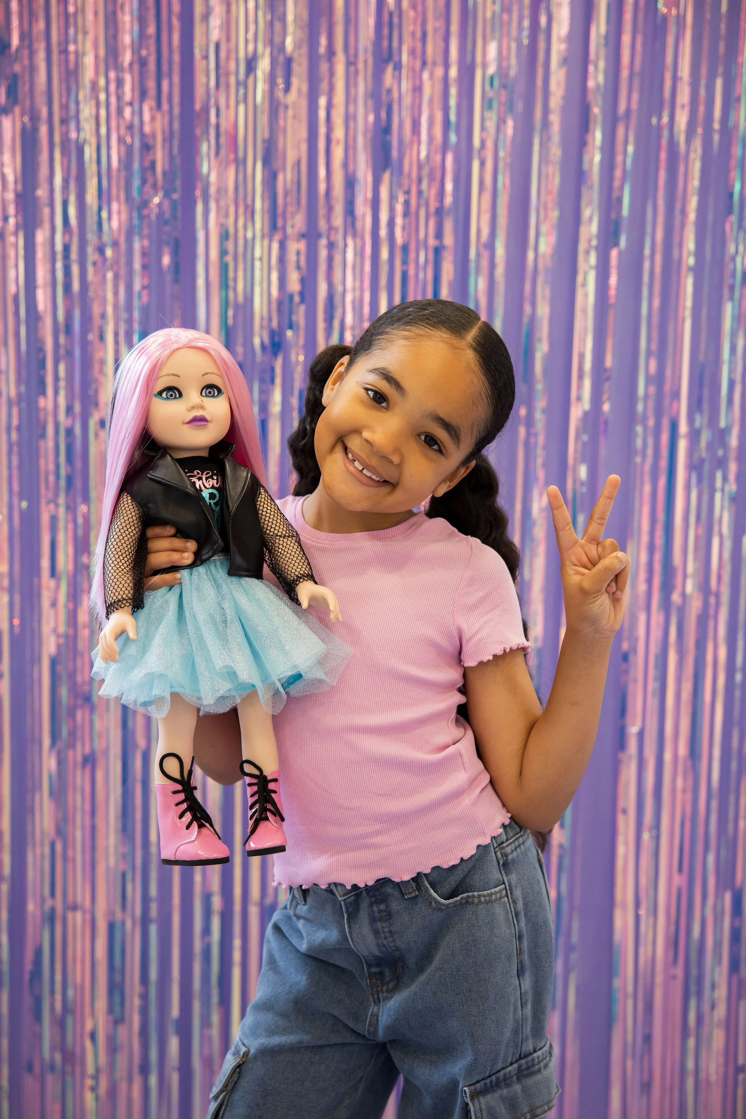 A young girl smiling holding her 18 inch Zombie inspired DesignAfriend doll. striking a pose for the camera.