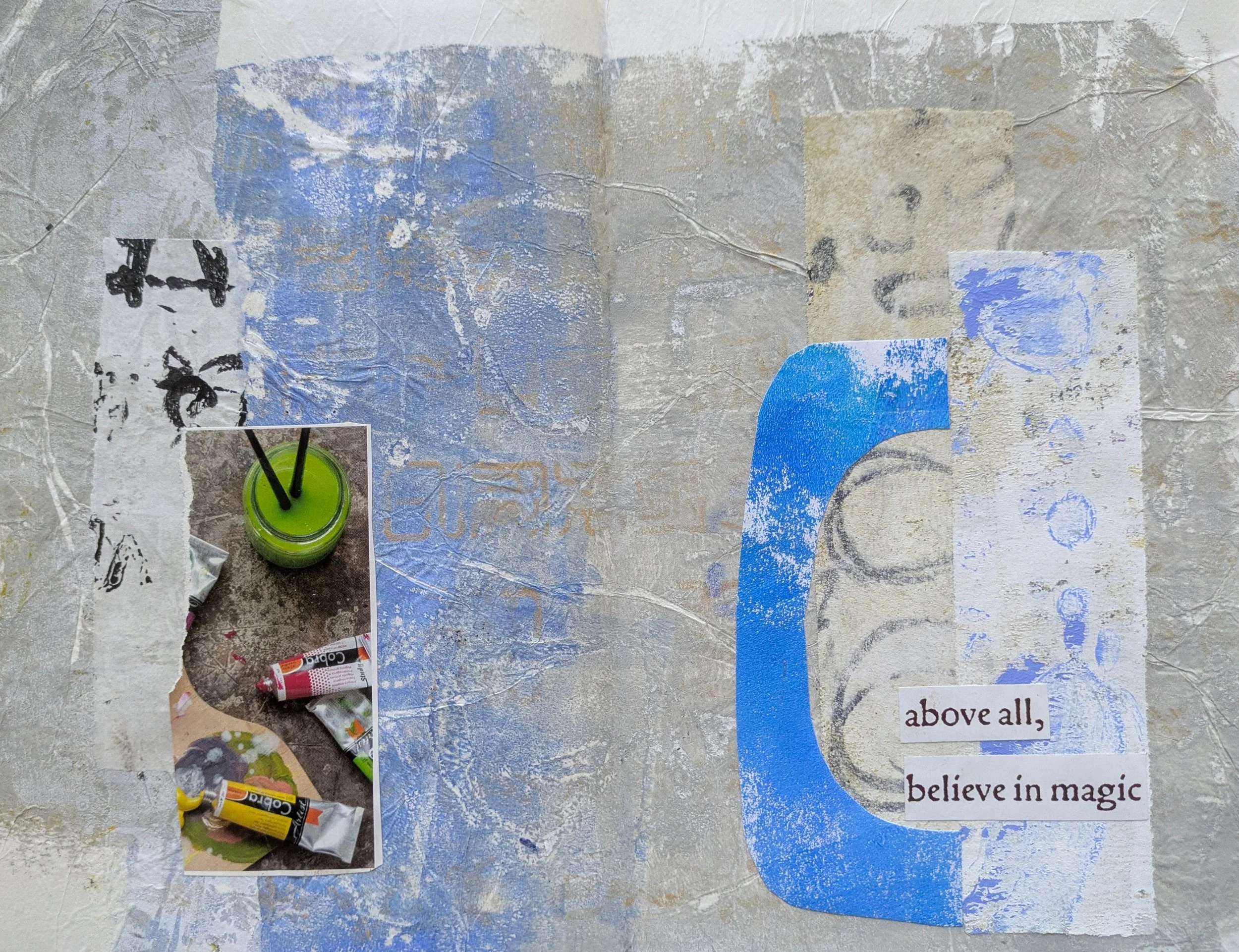 Collage on a textured surface with torn paper, a small photo of a jar of green paint with black stir sticks, a partially painted large blue lowercase letter 'g', and printed text reading 'above all, believe in magic'.