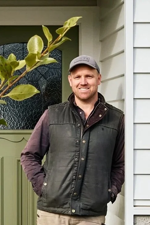 Nathan, CEO and owner of Homes By NH standing outside a completed custom home project in Geelong West, wearing outdoor casual work attire.