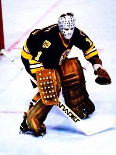 Gilles Gilbert dressed in a black and yellow uniform, wearing a helmet and pads, stands in a ready position on the ice rink.