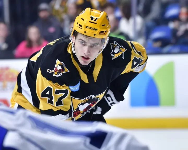 Chase Stillman wearing a black and yellow Pittsburgh Penguins jersey and a yellow helmet, on ice during a game.