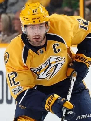 Mike Fisher wearing yellow and navy Nashville Predators jersey with the number 12 and a captain's 'C' on the chest, focused on the game.