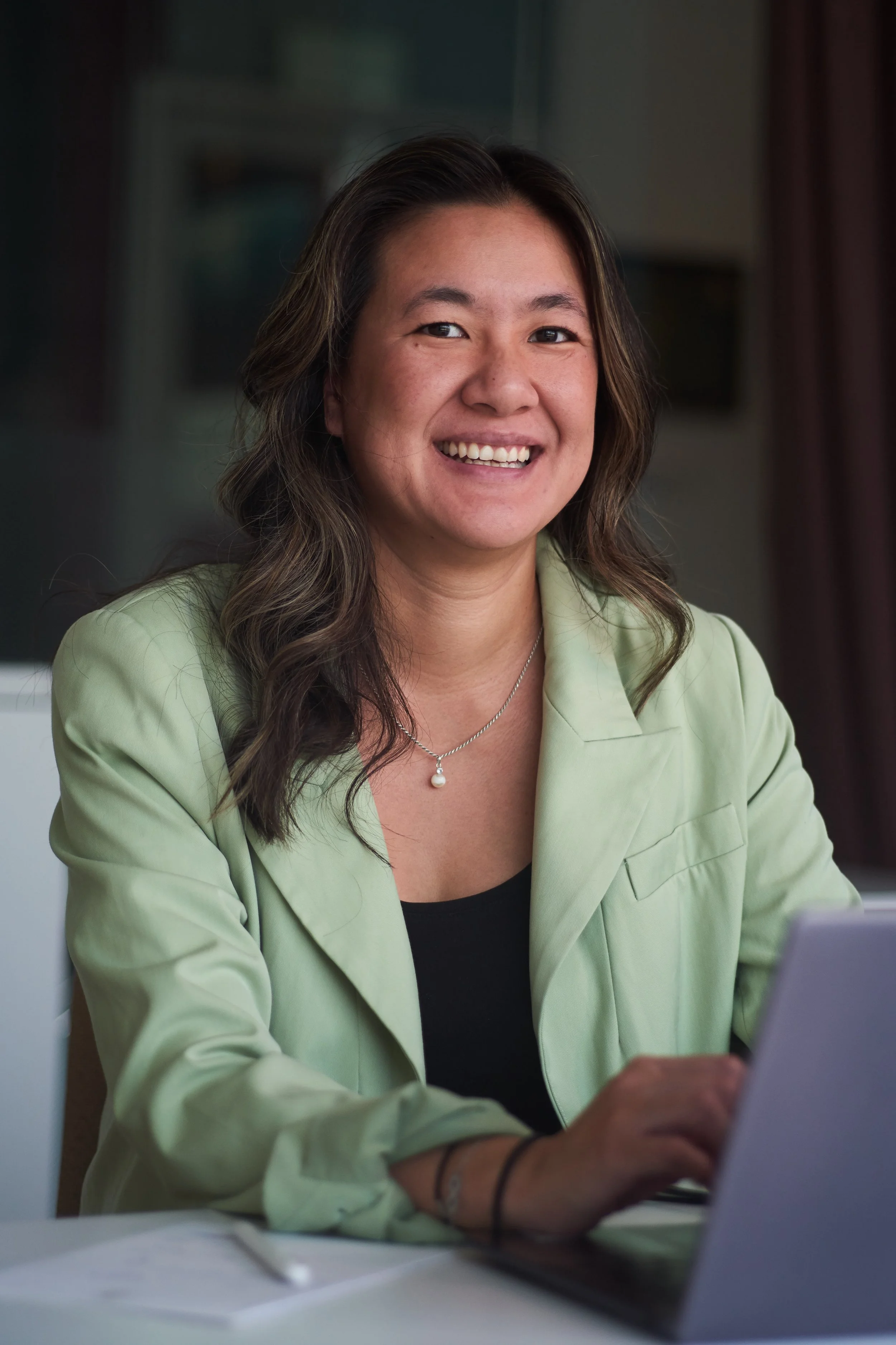 Tuong-Vy Dang, grunnlegger av The Reset Framework, sitter ved en laptop og smiler.