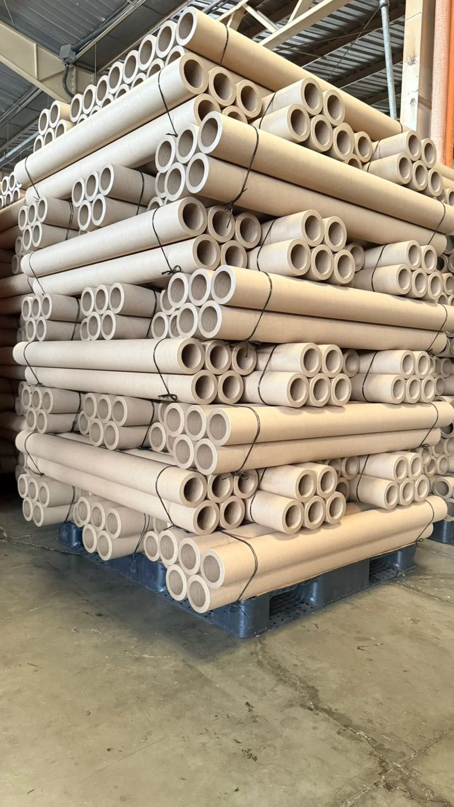 Gran pila de tubos de cartón apilados en un almacén de construcción.