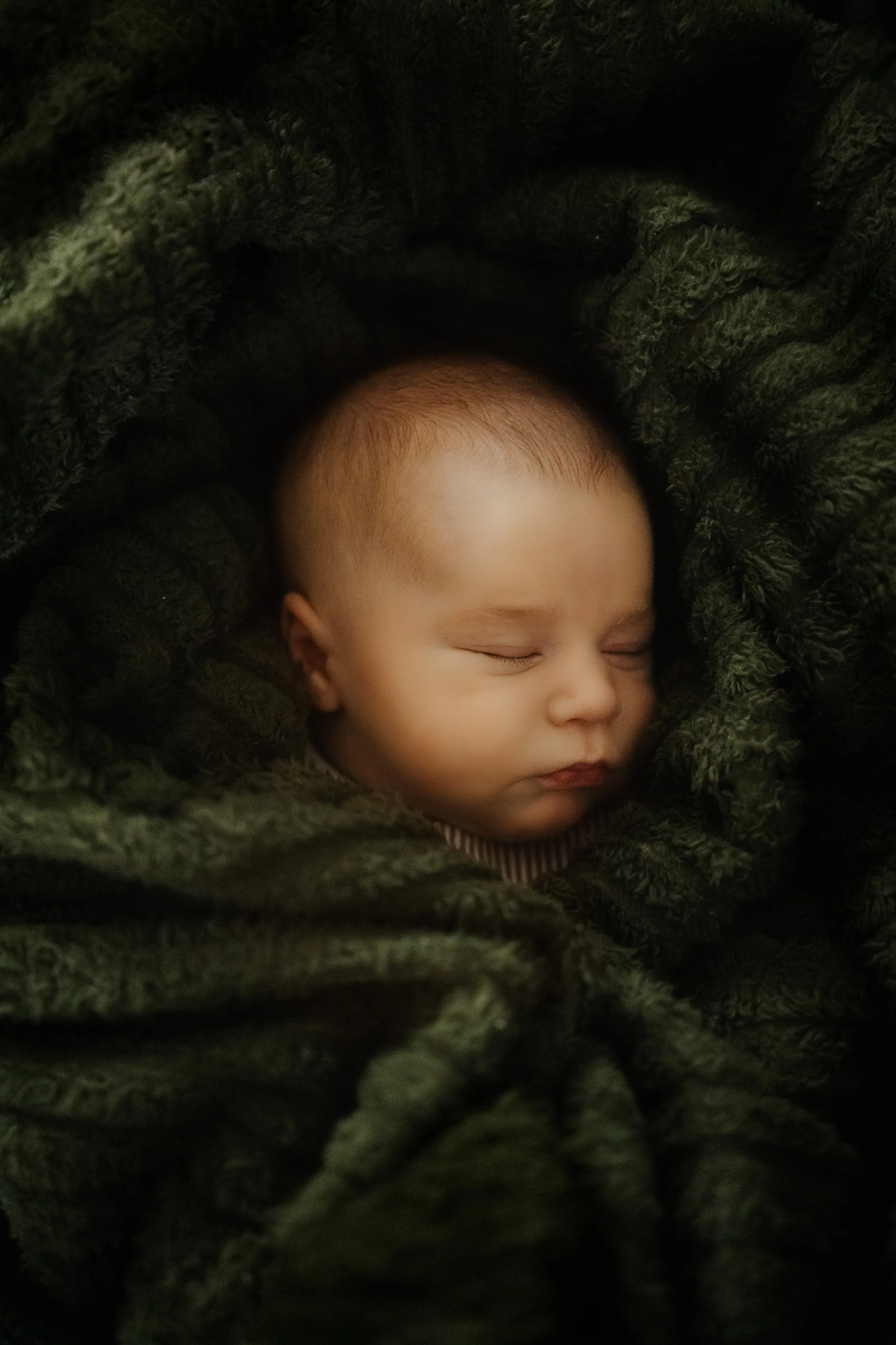 Un bébé endormi, entouré d'une couverture verte en velours