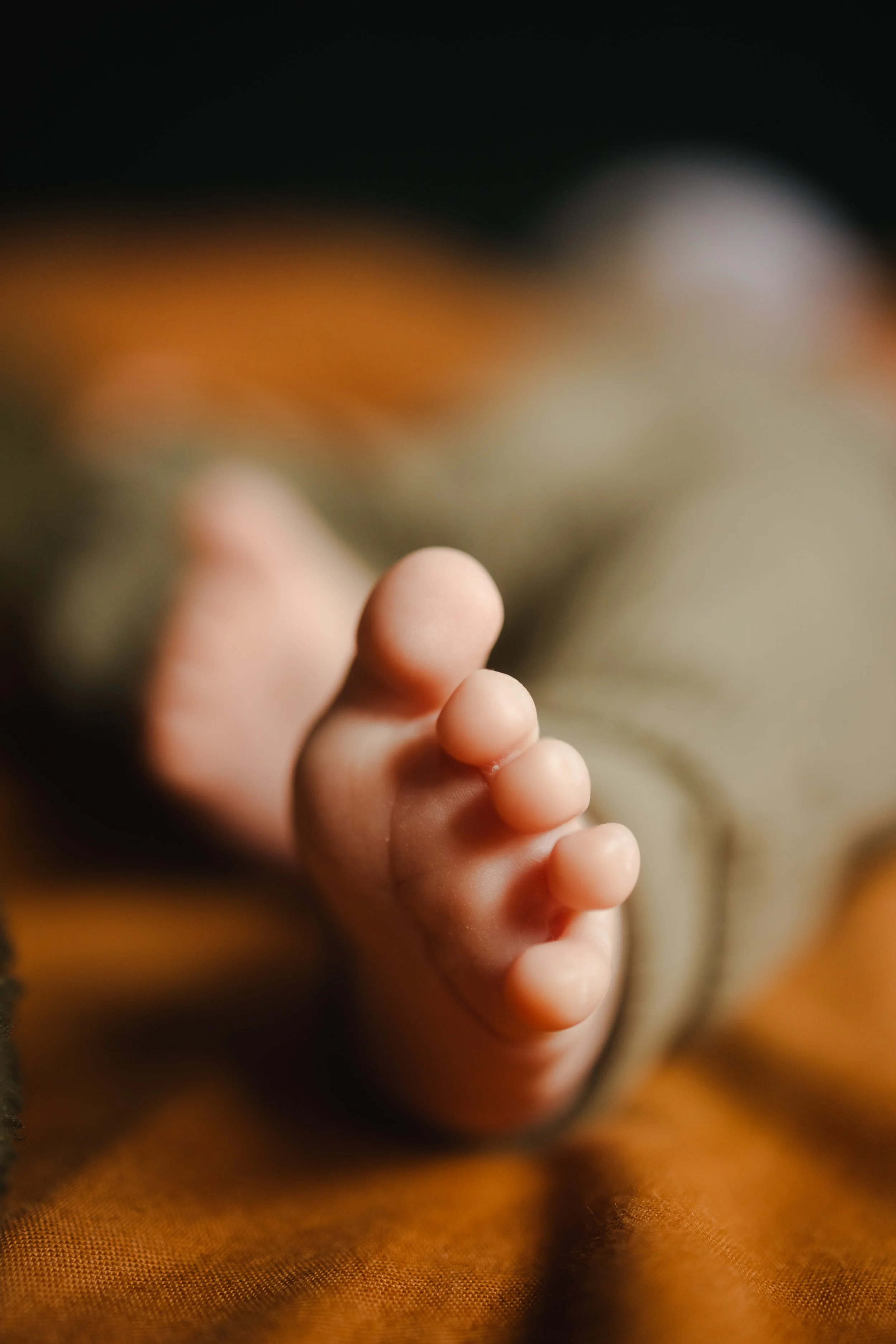 Gros plan d'une main ou d'un pied de bébé avec des doigts recourbés, en gros plan, image floue en arrière-plan.