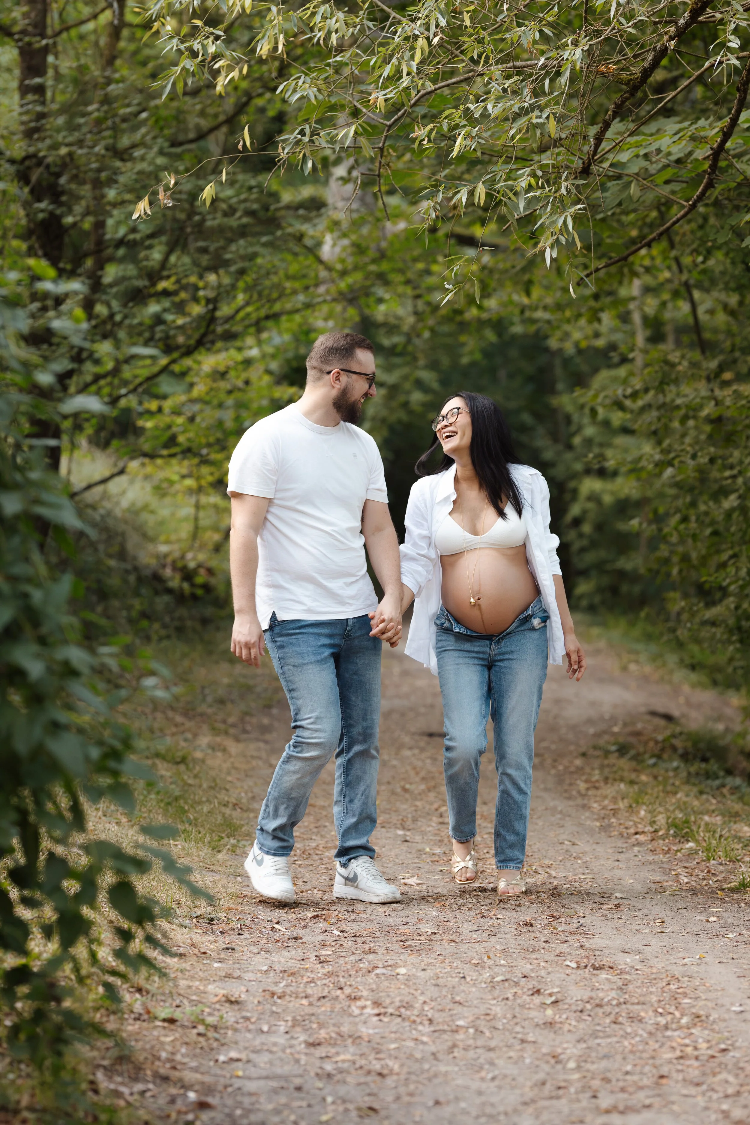 couple attendant un bébé, se baladant dans la forêt. La femme est enceinte