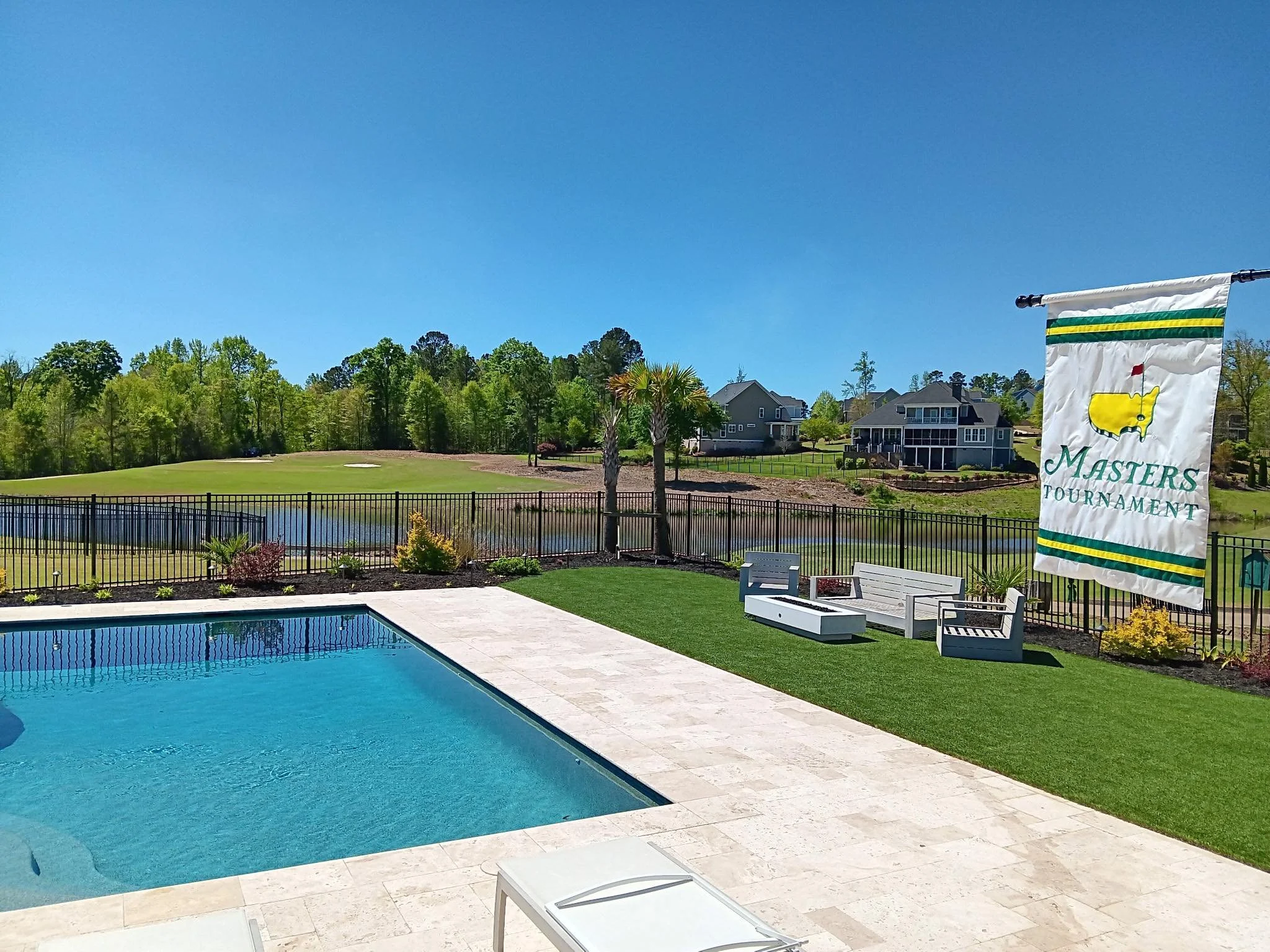 Vacation backyard with swimming pool, patio furniture, a golf course in the background, and a Masters Tournament banner.