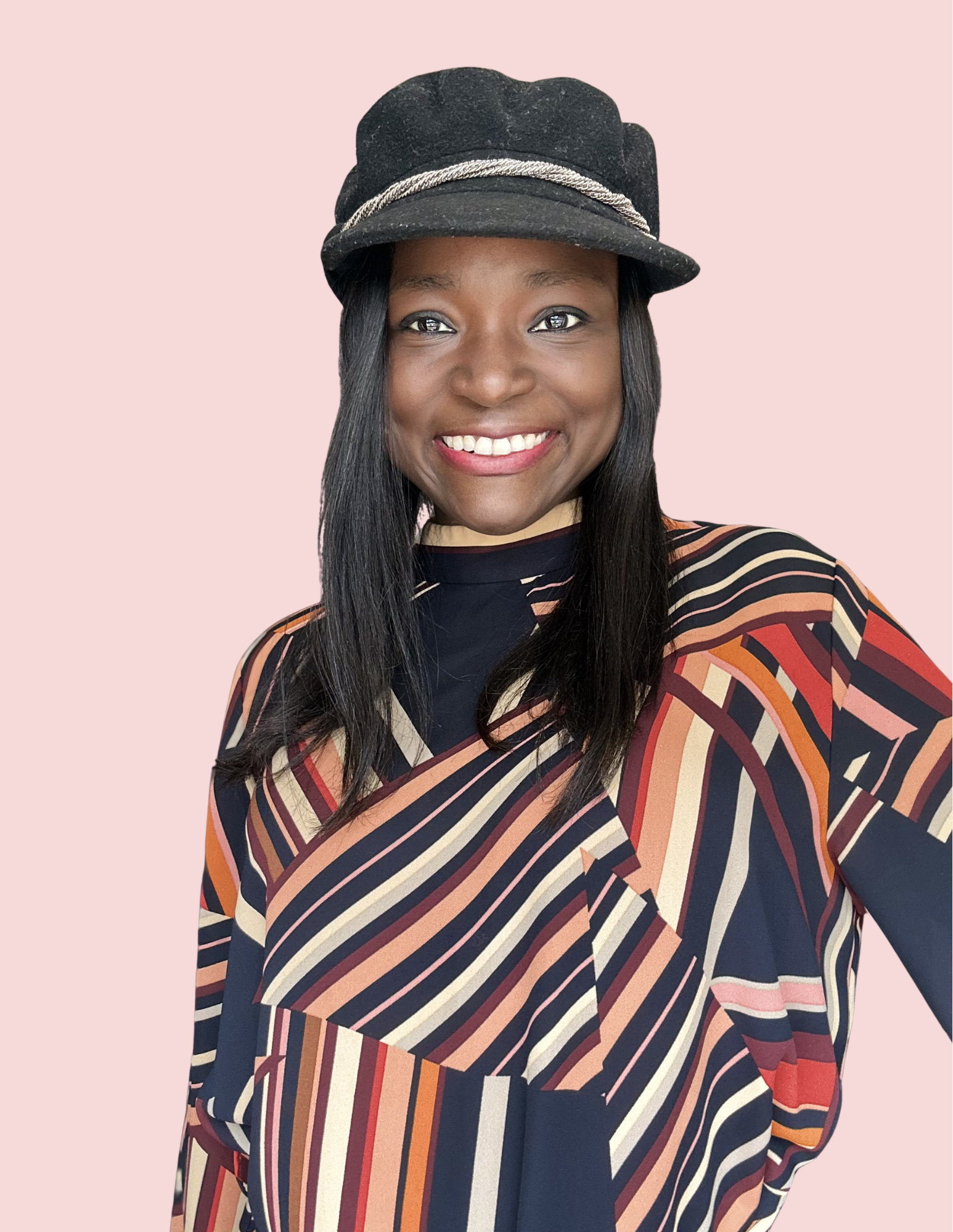 A woman with long black hair and a bright smile, wearing a black cap with a silver chain detail and a patterned dress or top with diagonal stripes in shades of red, orange, beige, and navy blue, set against a light pink background.
