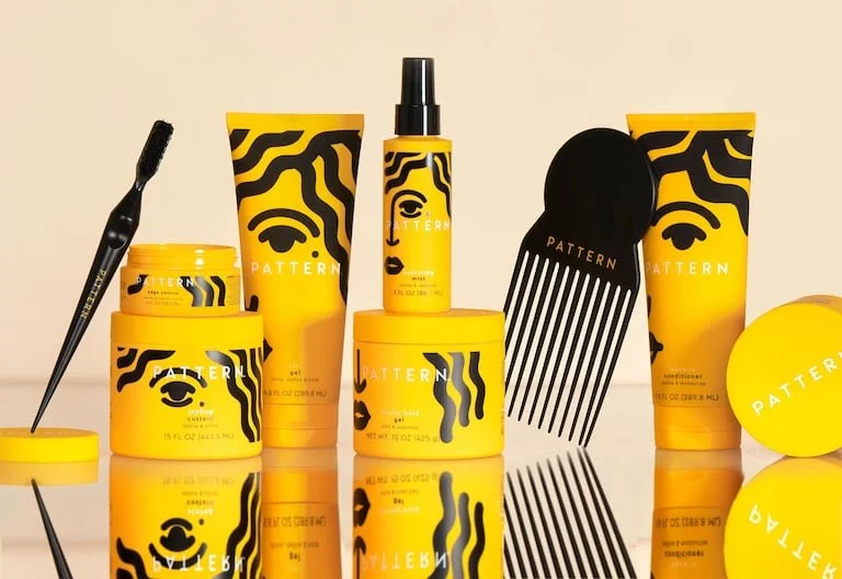 Collection of Pattern hair care products including cream, shampoo, conditioner, spray, and styling tools in yellow and black packaging.