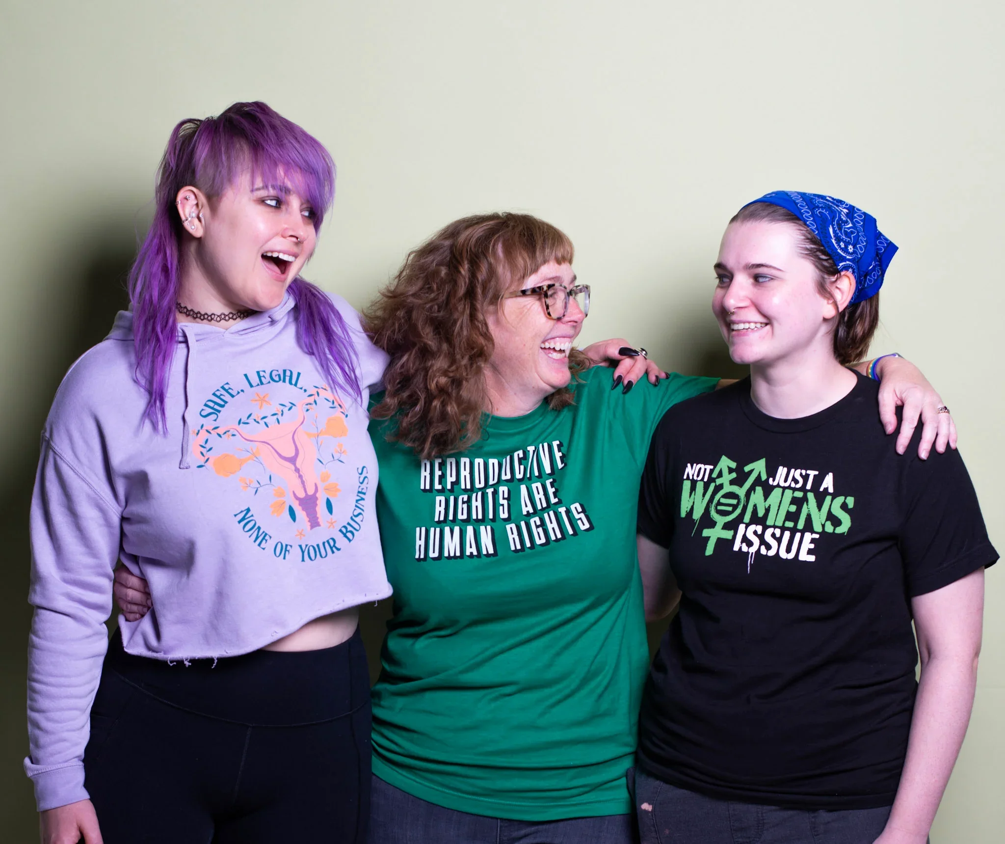 Three women wearing t-shirts with slogans about reproductive rights and women's rights.