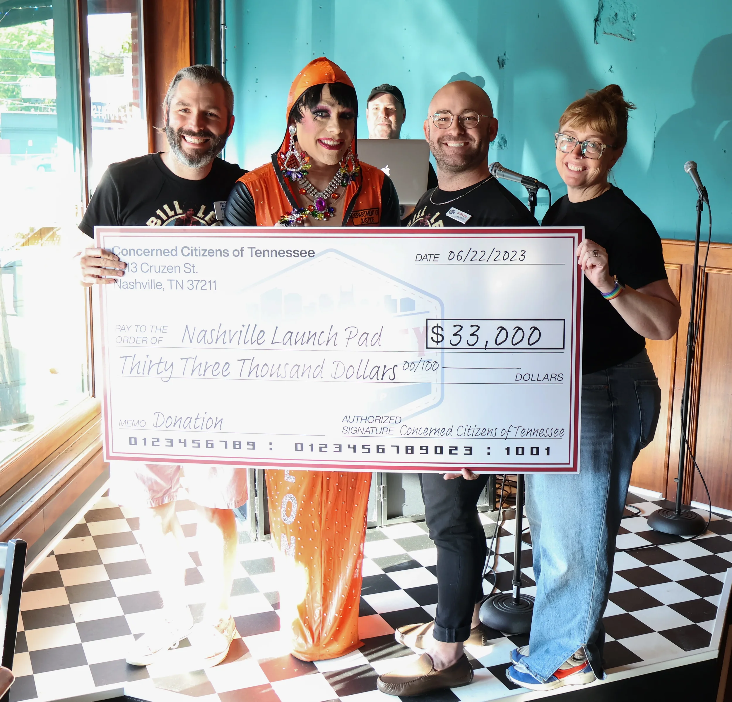 Four people standing with a donation check for $33,000 for Nashville Launch Pad, which provides LGBTQ+ affirming emergency housing for unhoused young adults.