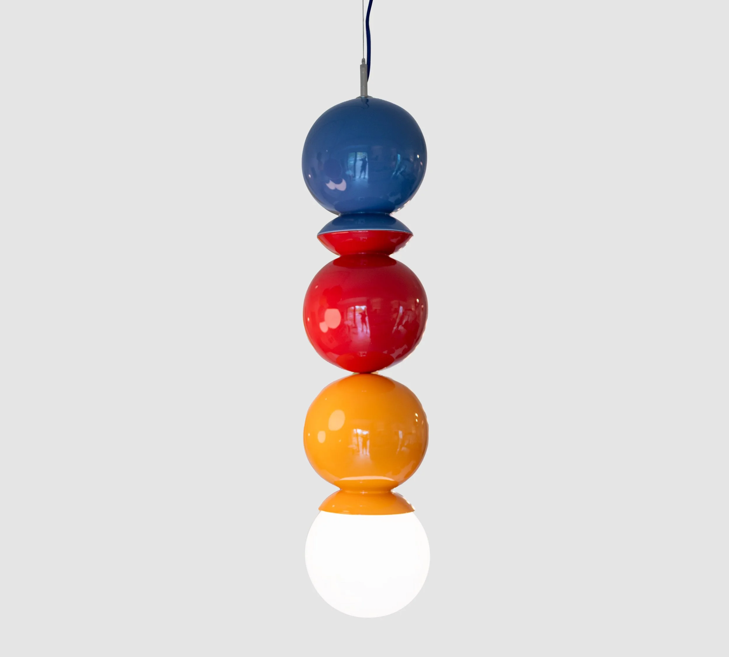 Purple, sumac red and orange peel ceramic Dot Dot Dot pendant, three glossy spheres joined at flared collars over a lit white globe, J Schatz Studio.