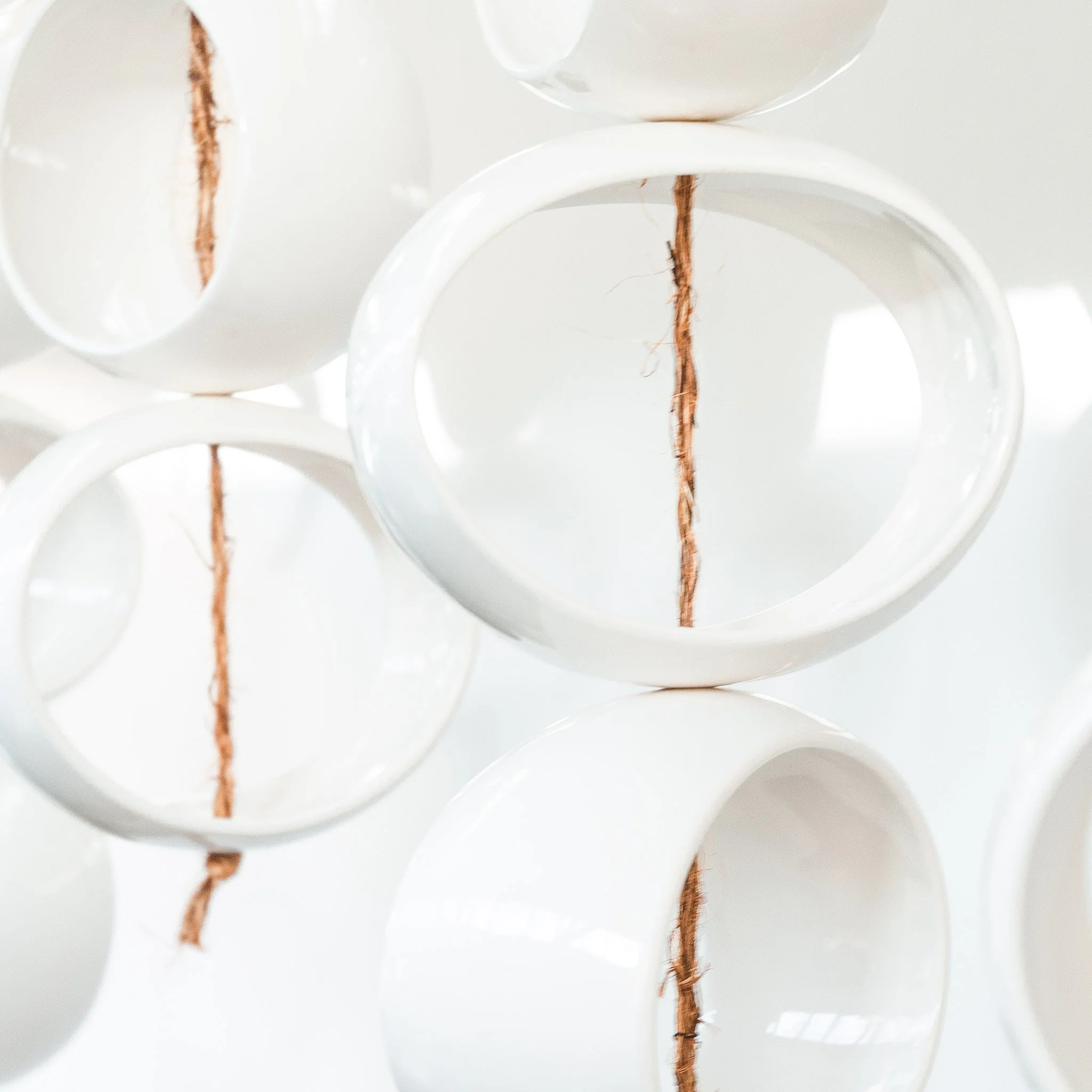 Cluster of glossy white stoneware orbs suspended in interior space
