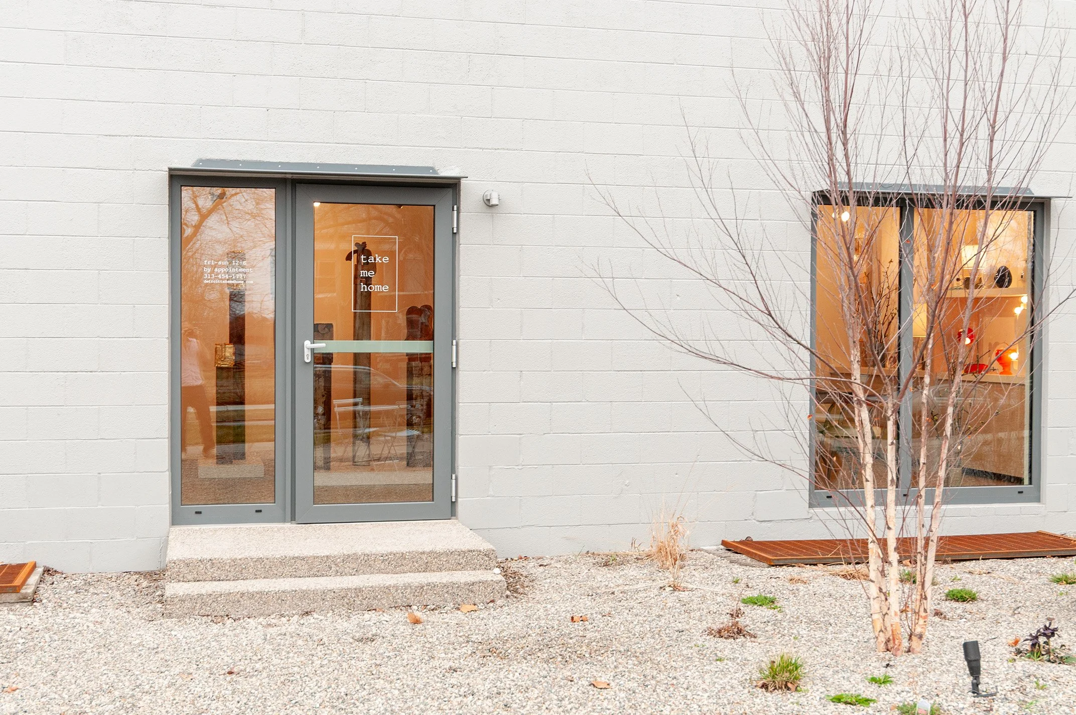 Exterior of Take Me Home gallery, Detroit, with take me home lettering on the glass door.