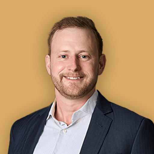 A portrait of a smiling man in a suit against a beige background.