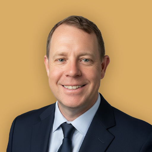 Professional headshot of a man in a suit and tie, smiling, against a beige background.