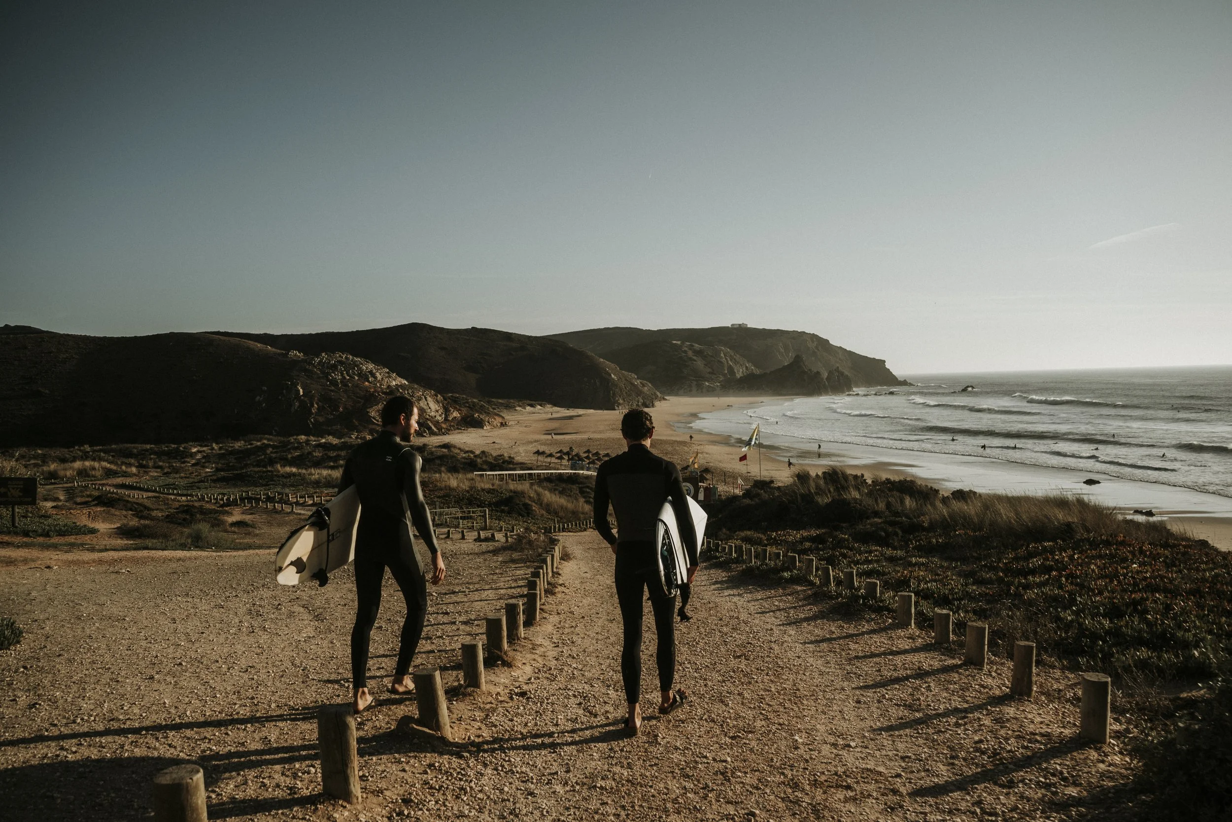 Surfer im Neoprenanzug am Strand der Algarve in Portugal beim Sonnenuntergang – festgehalten von Fotograf Arif Türkmen.