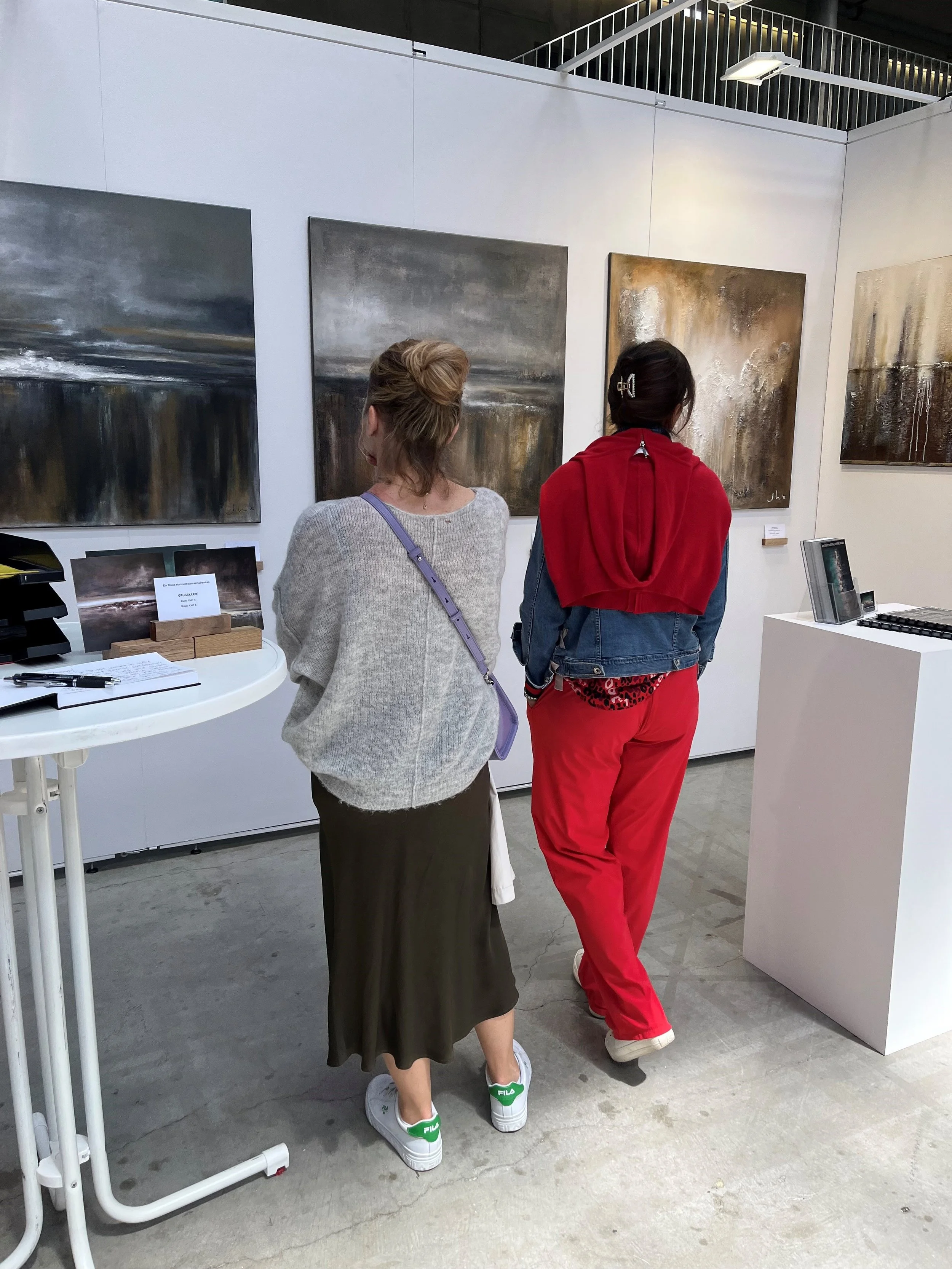 Zwei Frauen betrachten abstrakte Gemälde in einer Kunstgalerie.