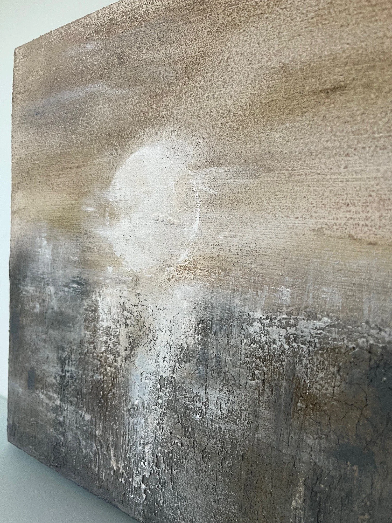 Abstraktes Kunstwerk mit Erdtönen, strukturierten Oberflächen und einem weißen Kreis in der Mitte.