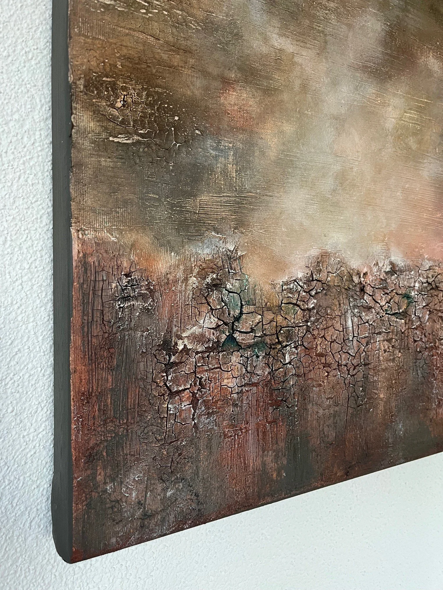 Ein abstraktes Gemälde mit warmen Erdtönen und rissigen Texturen, auf Leinwand aufgespannt und an einer weißen Wand angebracht.