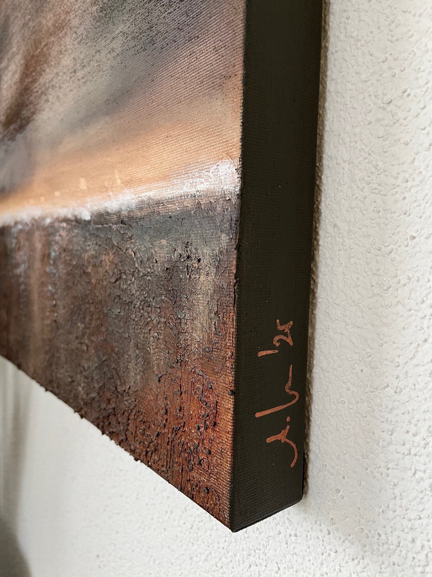 Nahaufnahme eines abstrakten Gemäldes auf Leinwand, das an einer weißen Wand hängt. Die Ecke des Gemäldes ist sichtbar mit der Signatur 'juli' am schwarzen Rahmen.