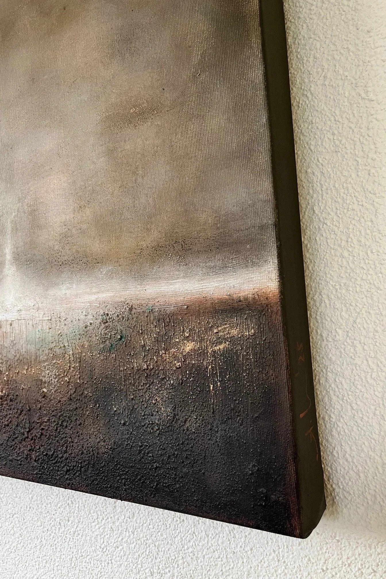 Nahaufnahme eines Gemäldes mit abstrakten, dunklen und erdigen Farben, an der Wand montiert.