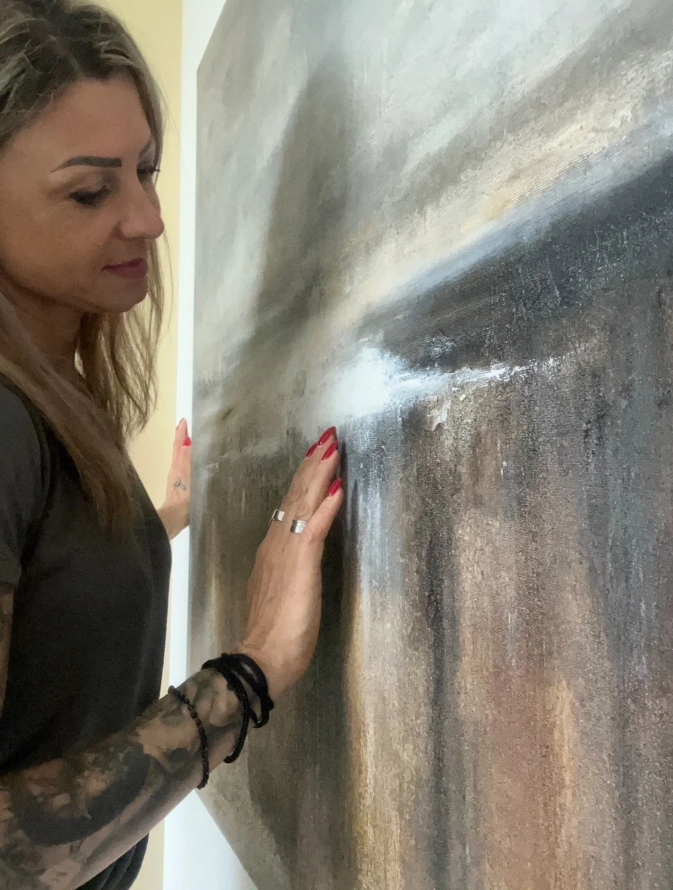 Frau berührt ein abstraktes Gemälde mit einer Hand