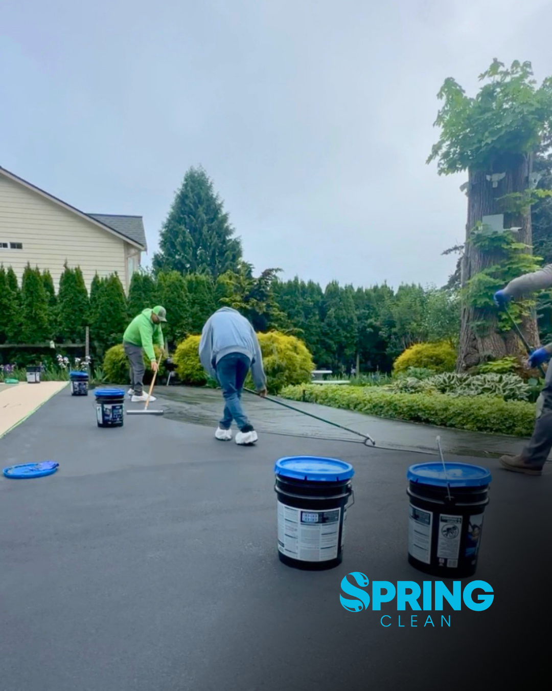 Spring Clean crew applying asphalt sealcoat to a residential driveway for uniform coverage and surface protection.