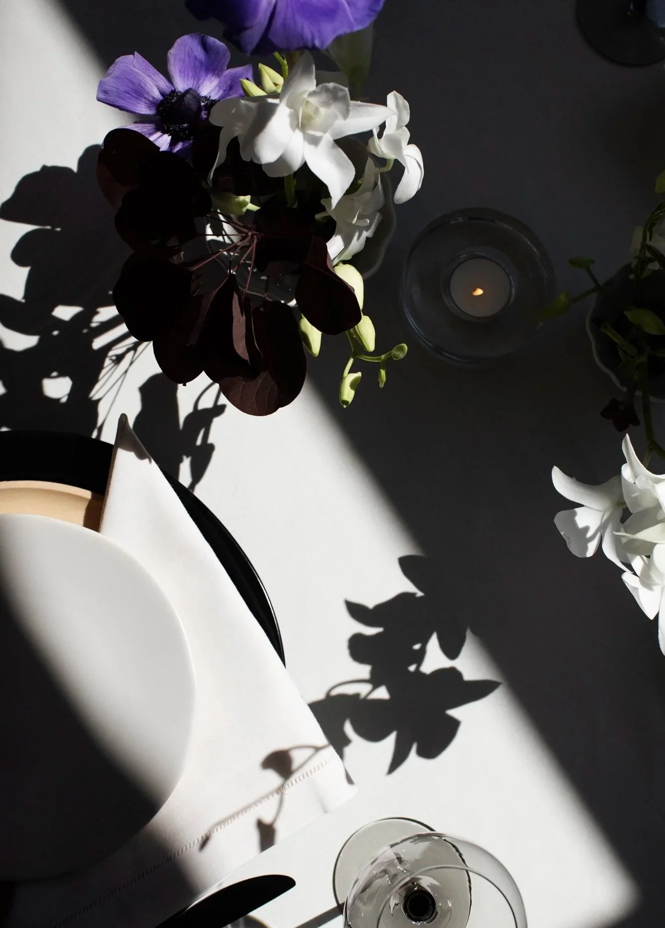 Moody wedding reception table with purple anemone florals, deep burgundy foliage, and candlelight — unique wedding venue in Minnesota