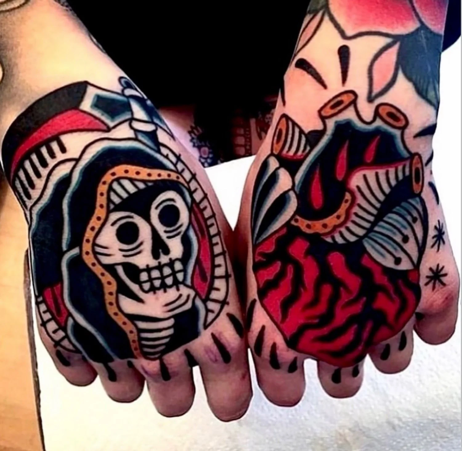Tattooed fists, featuring skull and rose designs in traditional style.