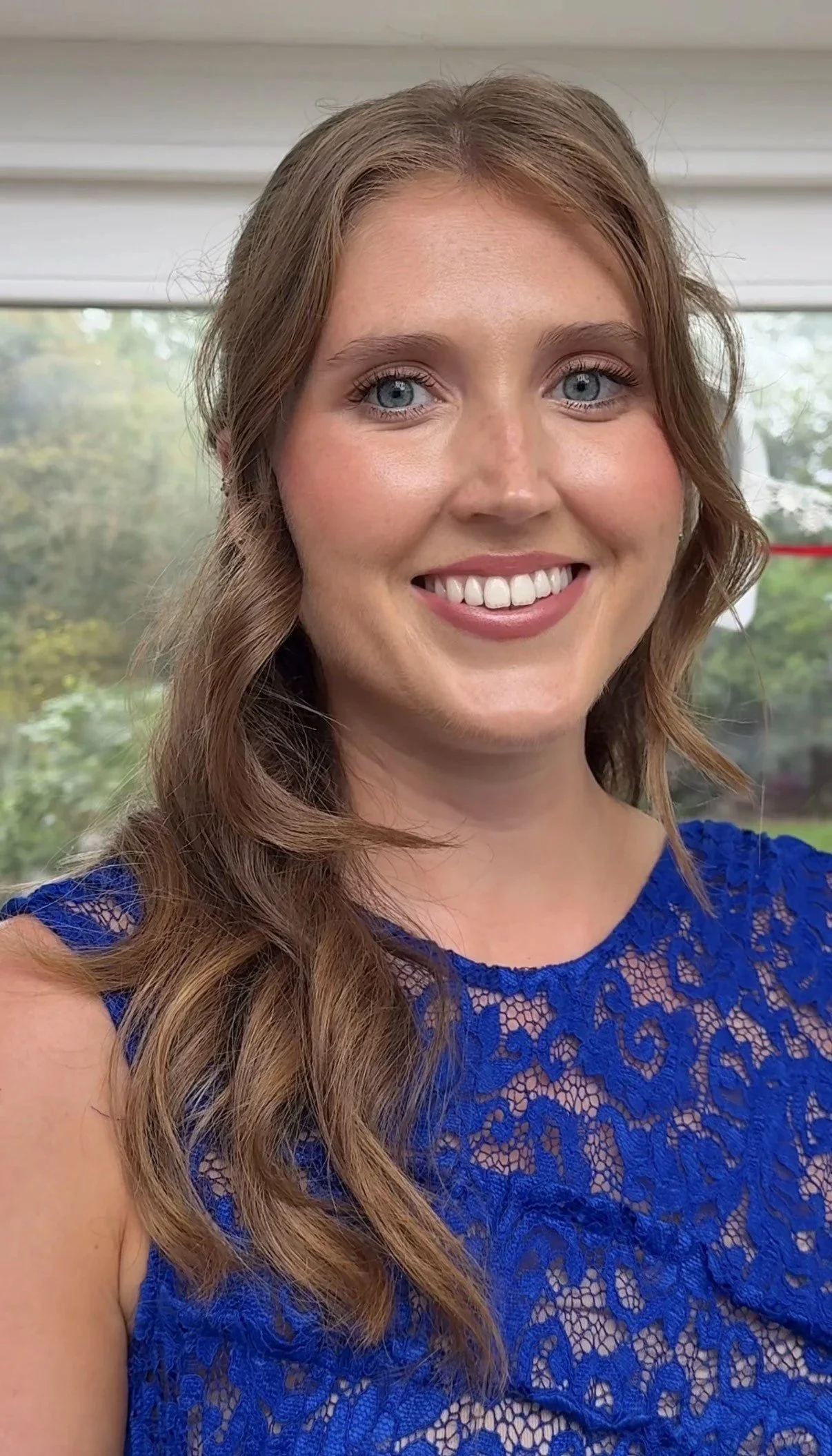 A bridesmaid smile at the camera with glowy, skin-focused makeup applied & a soft pink lip