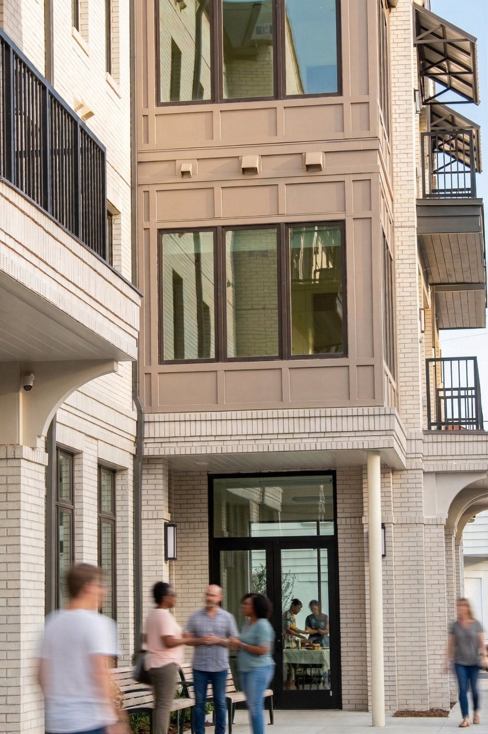 Group of people standing and chatting outside a modern apartment building with large windows and balconies.