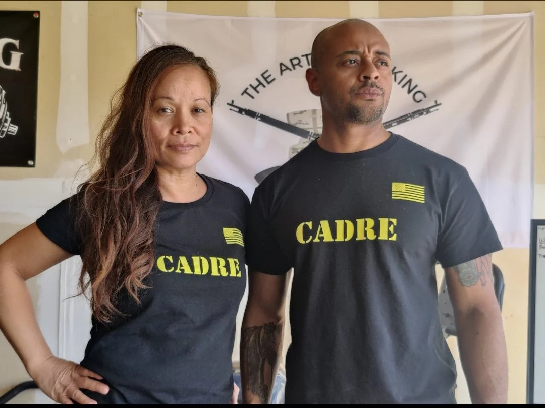 Two people wearing black T-shirts with 'CADRE' printed in yellow.