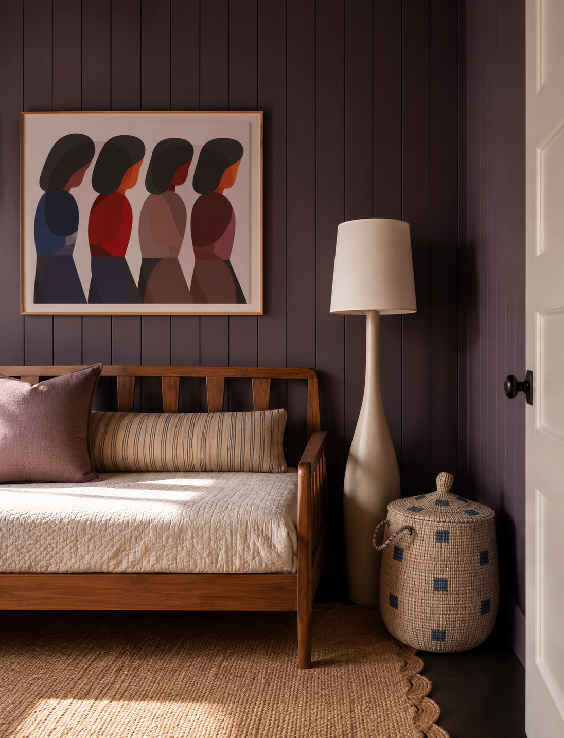 Room with a design within reach bed, framed artwork by Geoff McFetridge , a tall beige floor lamp, woven basket, and a dark mauve paint scheme by Farrow and Ball