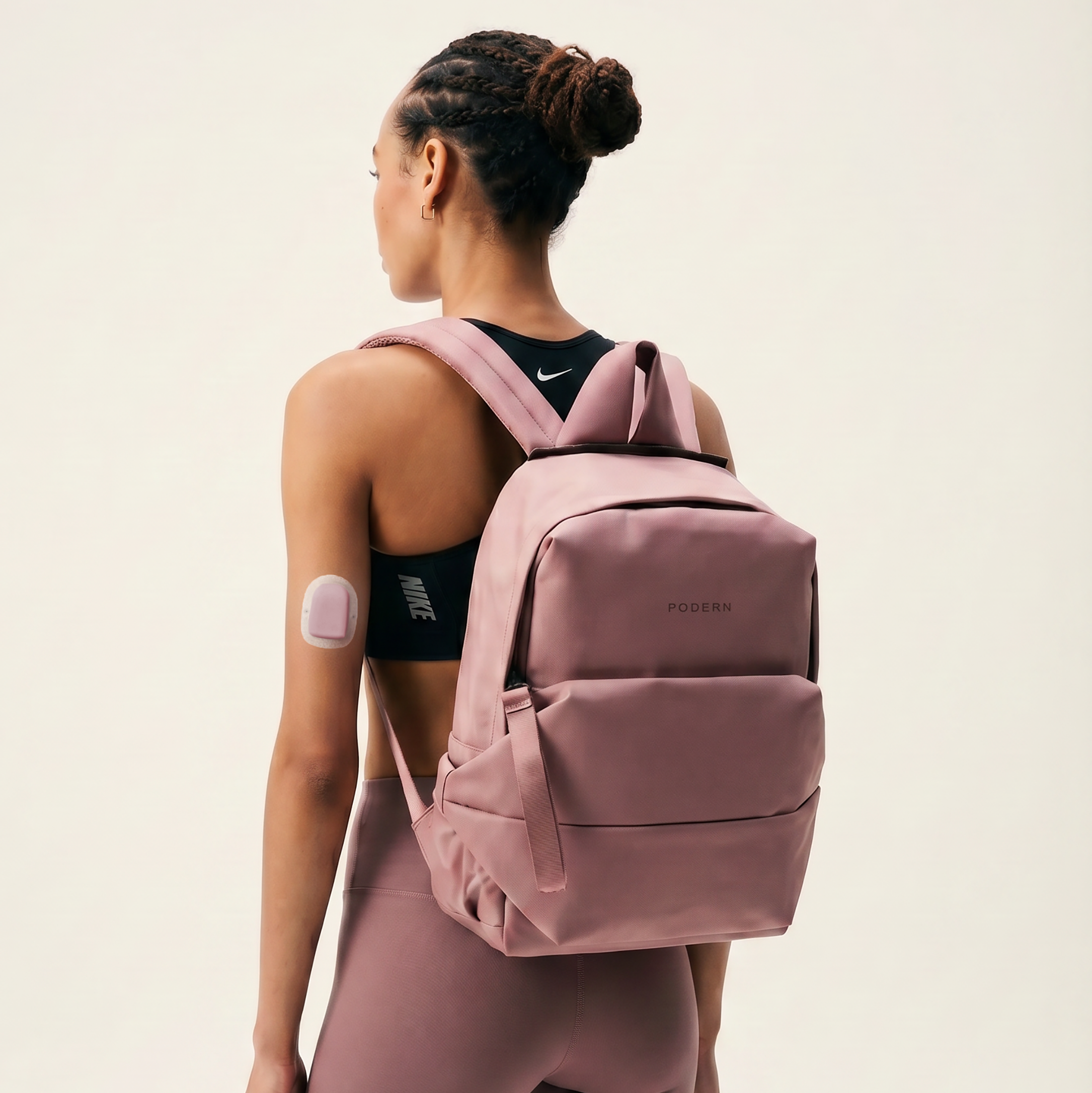 Young black woman, in Nike Lab training gear, wearing a Omnipod Cover on her Insulin Pump, wearing a elevated and technical waterproof backpack, and mauve ALO leggings.