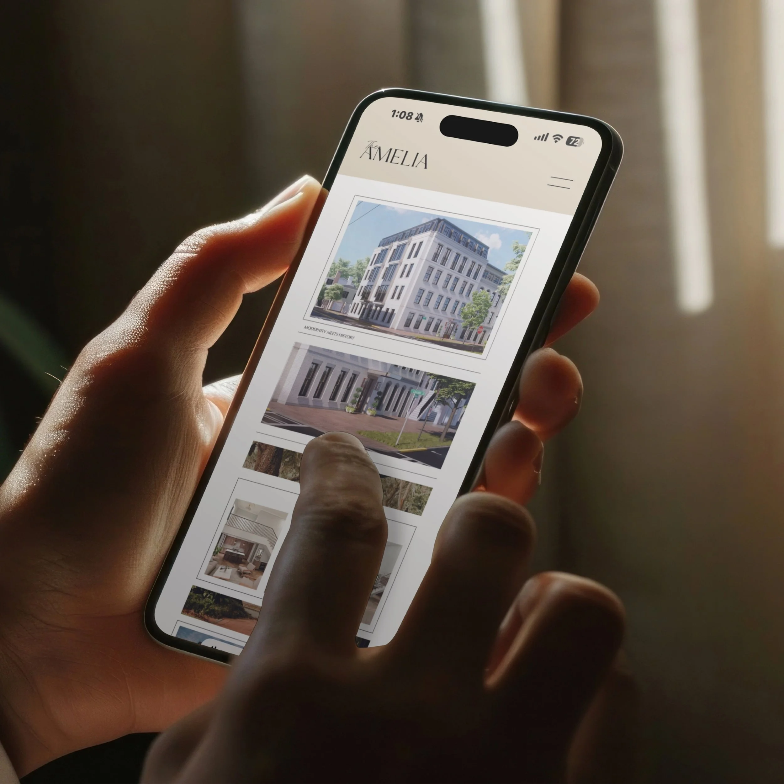 A person holding a smartphone displaying a real estate website with images of modern buildings or apartments.