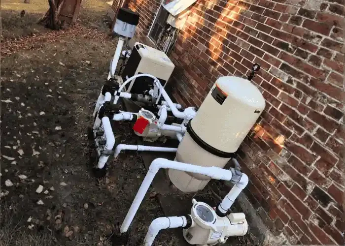 Pool filter and pump system installed outside against a brick wall.
