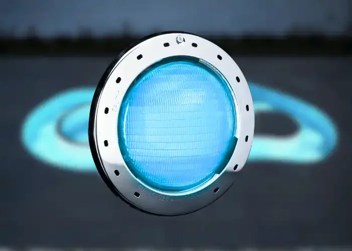 Blue illuminated traffic or warning light mounted on dark surface, casting light and shadow patterns.