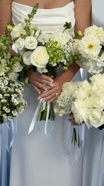 Woman holding a bouquet of white and green flowers at a wedding.