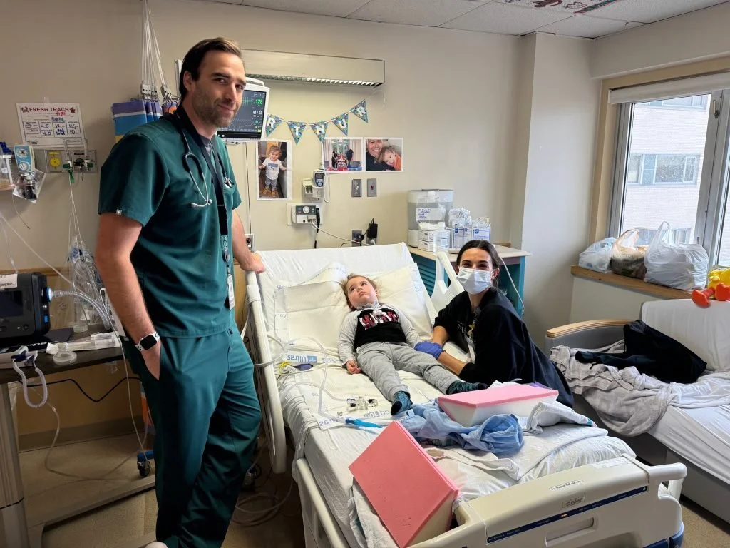 Un médecin et une infirmière prennent soin d'un jeune garçon allongé dans un lit d'hôpital, dans une chambre d'hôpital bien éclairée.