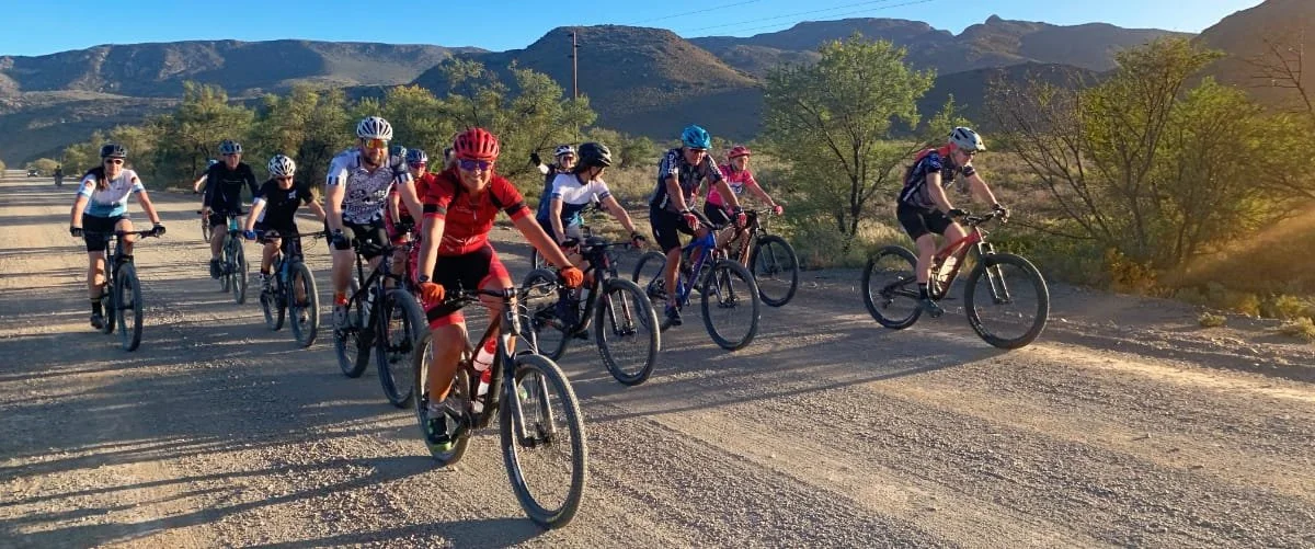 A group of people riding mountain bikes on a dirt road in a mountainous area during daytime.
