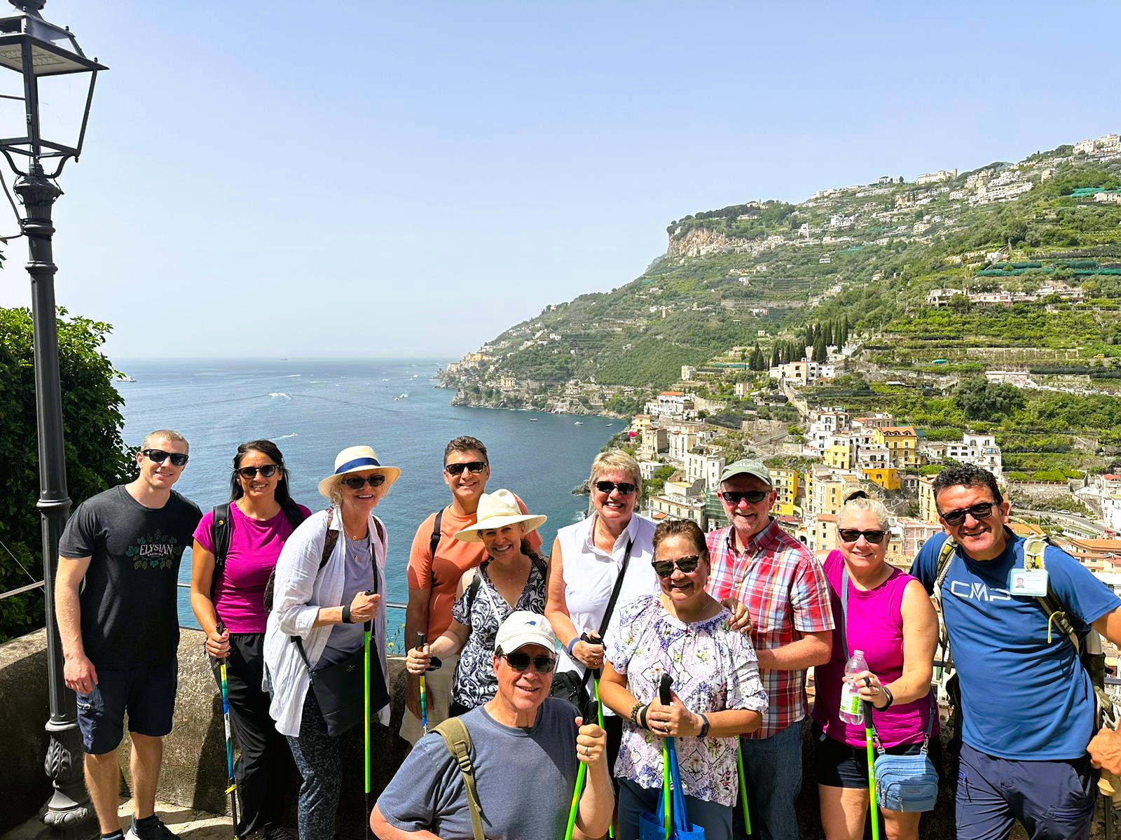 Group of eleven people standing outdoors, overlooking a coastal town built on hills with colorful buildings, under a clear sky.