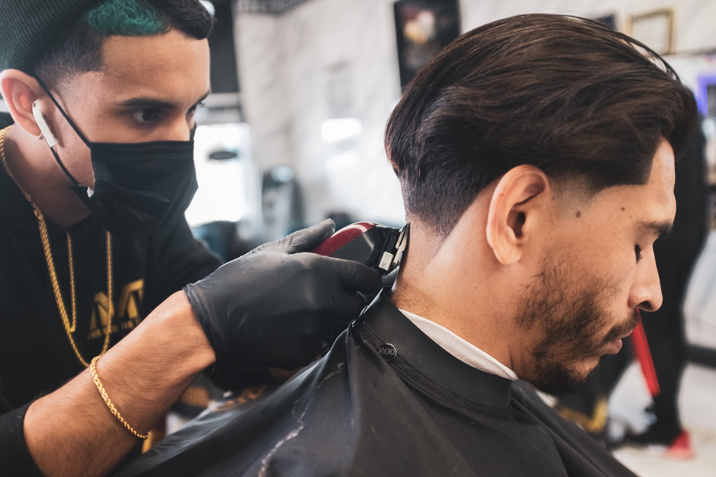 Barber giving a man a haircut in a salon, using clippers on the man's neck.